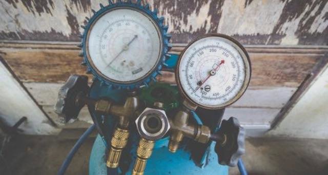 HVAC manifold gauges connected to a refrigerant tank for system diagnostics by Brimhall Maintenance Services in Cordova, TN