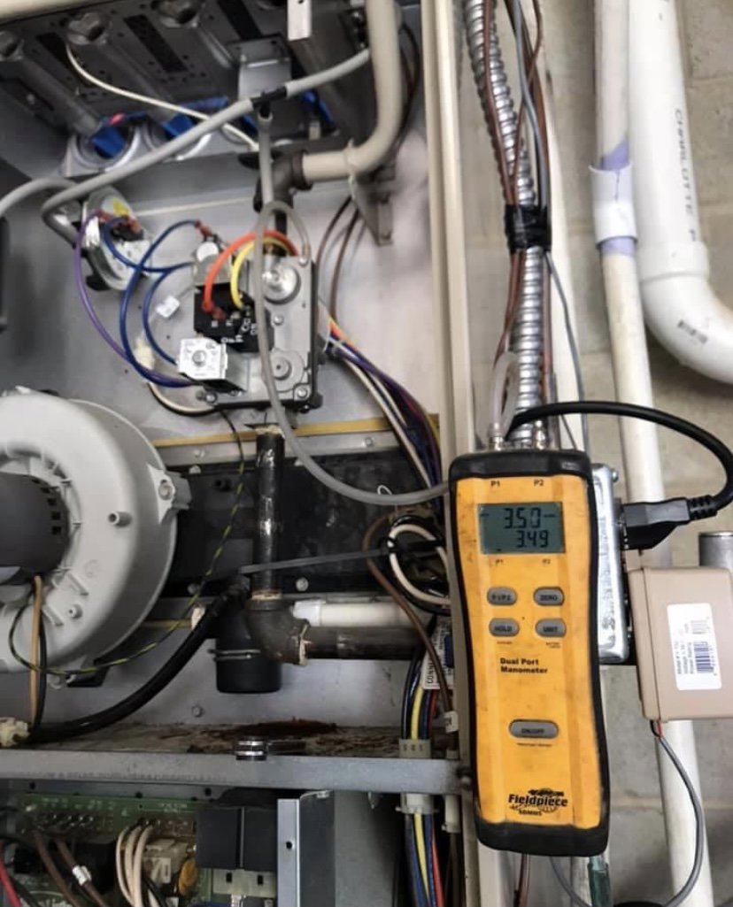 An HVAC technician using a manometer diagnostic tool to test a furnace unit for Systematic Heating & Air in Winston-Salem, NC.