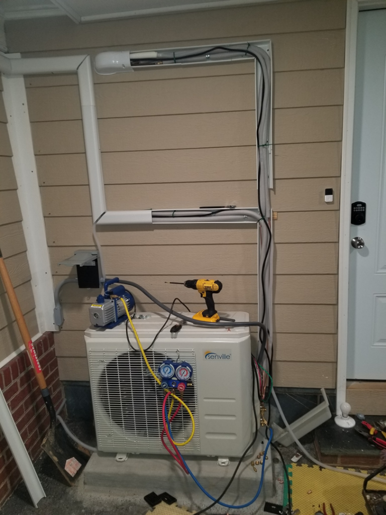 HVAC technicians performing a mini-split installation with tools and gauges at a home in Roanoke, VA by A.C. Installing.
