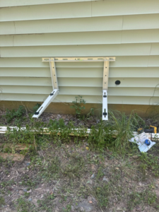 An HVAC outdoor unit mounting bracket installed on a house wall by DD HVAC PROS in Charlotte, NC.