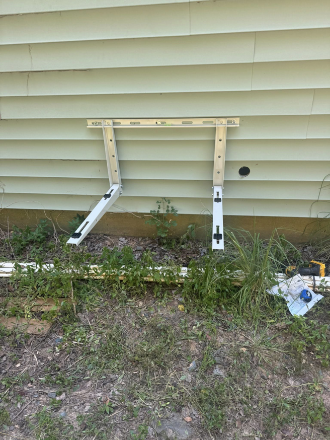 An HVAC outdoor unit mounting bracket installed on a house wall by DD HVAC PROS in Charlotte, NC.