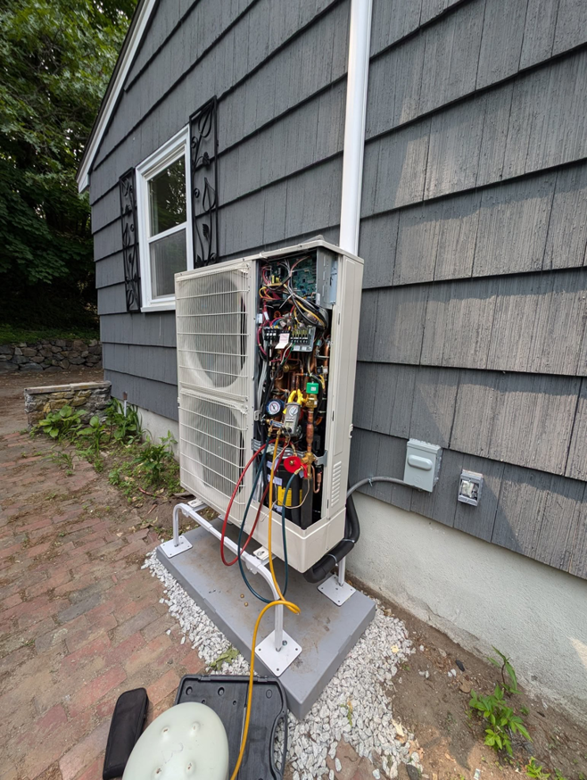 An outdoor HVAC unit undergoing service or repair with connected gauges by Frontier 44 Corp. in Melrose, MA.