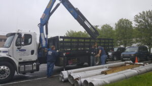 Workers using a crane truck to deliver large pipes for an HVAC project by Clean Air Quality Service Inc in Hawthorne, NY