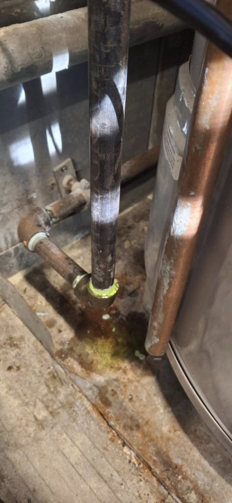 Close-up of corroded HVAC piping with green residue and liquid, indicating a leak repair by J Hannah Mechanical Inc in Saco, ME.