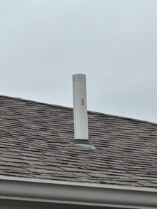 A white PVC vent pipe for an HVAC system installed through a residential roof by Freeman Heat & Air in Roland, OK