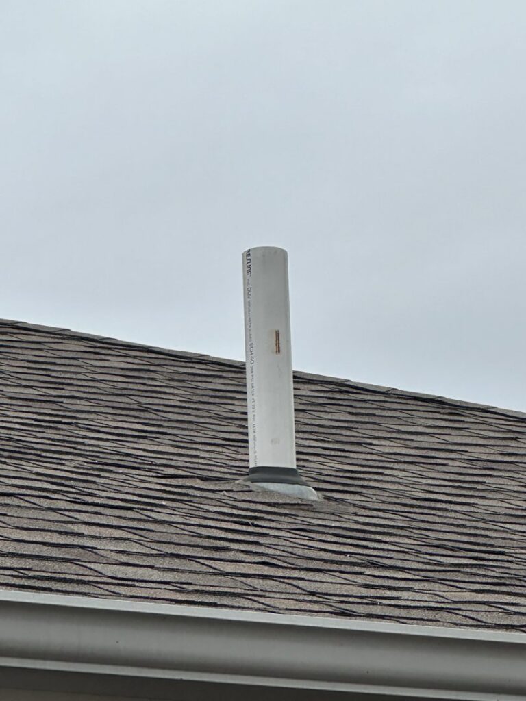 A white PVC vent pipe for an HVAC system installed through a residential roof by Freeman Heat & Air in Roland, OK