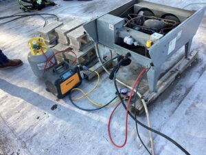 Refrigerant tanks and gauges connected to a commercial rooftop HVAC unit during service by Service Champions Heating & Cooling in Aurora, IL.