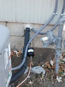 Close-up of outdoor HVAC refrigerant and gas lines with a filter/dryer, installed by A-1 HVAC in Kansas City, KS.