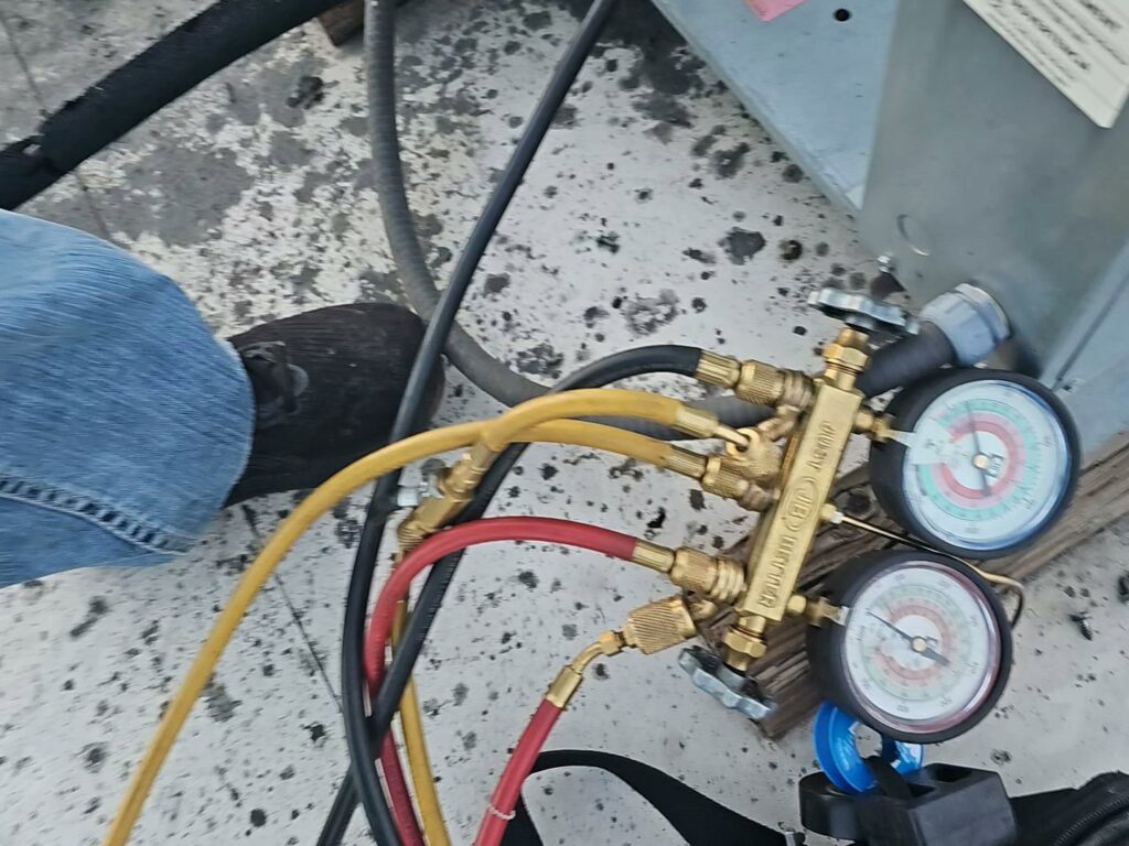 Close-up of refrigerant gauges connected to an HVAC system during service by Henry Refrigeration & Hvac Utah in Ogden, UT.