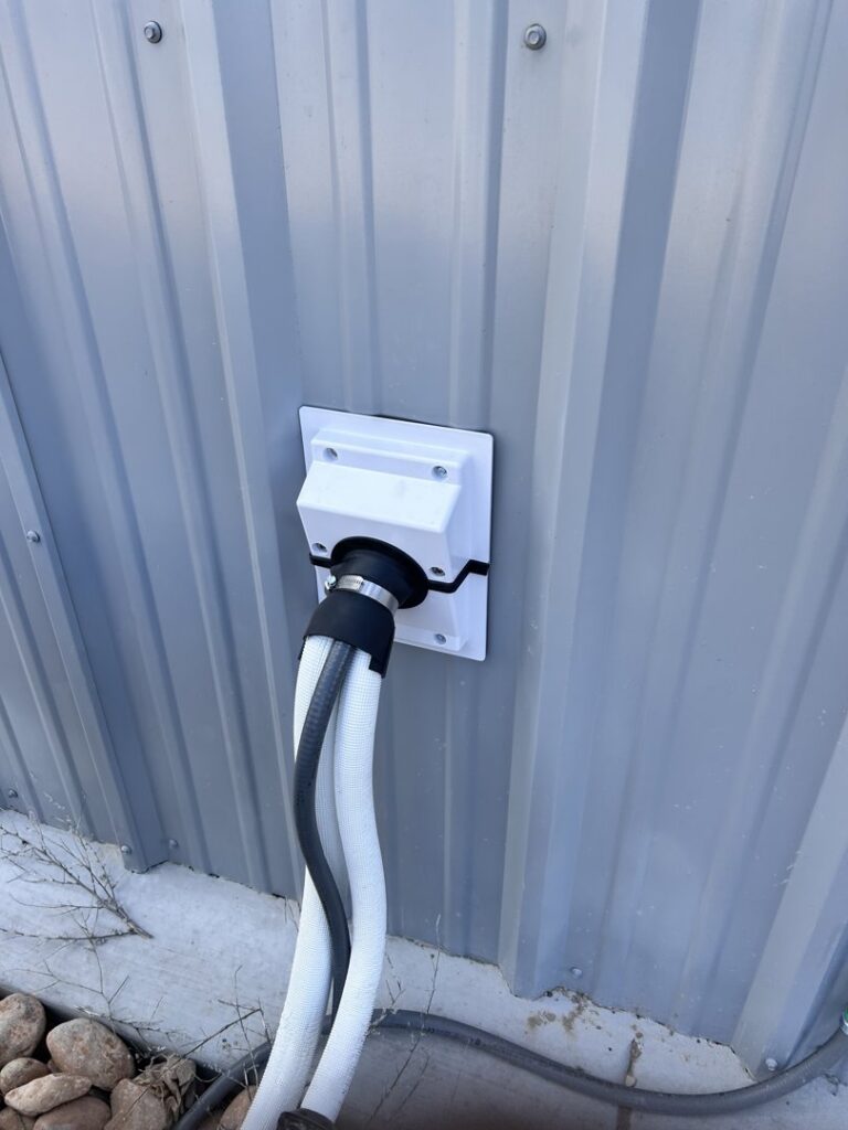 Close-up of HVAC refrigerant lines entering a building through a wall penetration, installed by KCC Mechanical, LLC in Sandy, UT.