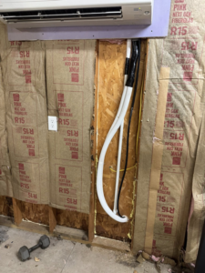HVAC refrigerant lines and electrical conduit running through a wall by DD HVAC PROS in Charlotte, NC.