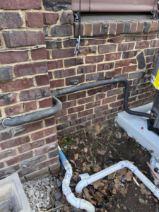 HVAC refrigerant lines and condensate drain piping installed along a brick wall by Indoor Weather Solutions LLC in Broken Arrow, OK.