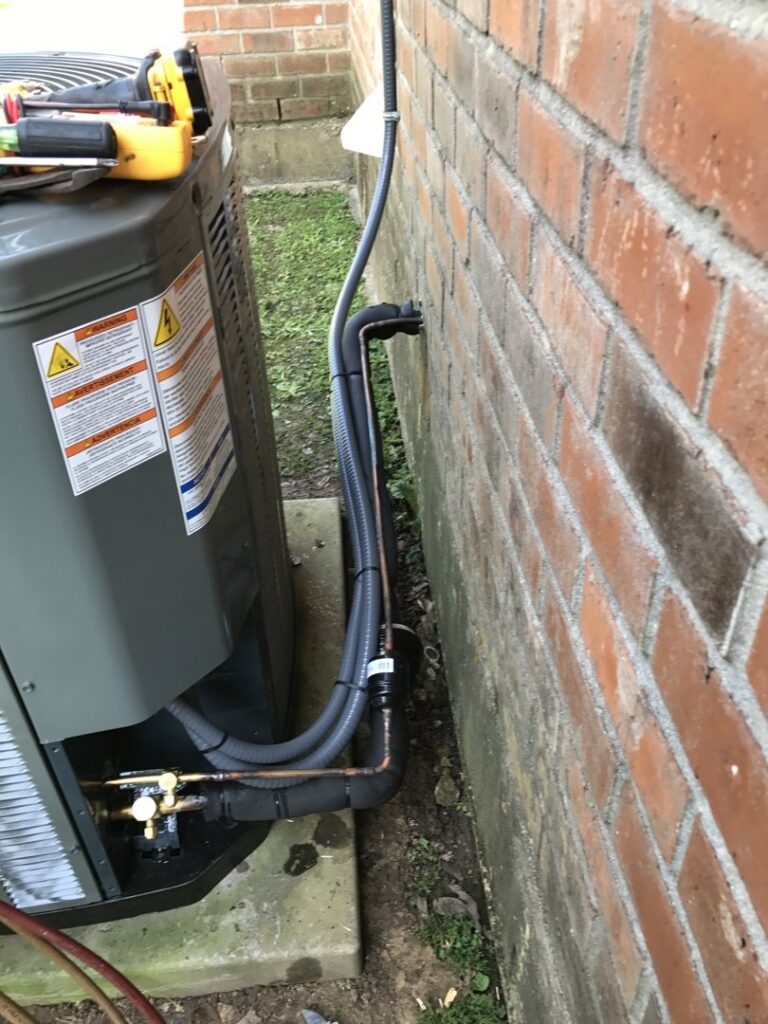 Close-up of HVAC refrigerant lines and electrical connections on an outdoor unit by Alpha HVAC LLC in Alexandria, LA.