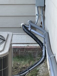 Close-up of HVAC refrigerant lines and electrical conduits professionally installed by Kelley Brothers LC in Livonia, MI.