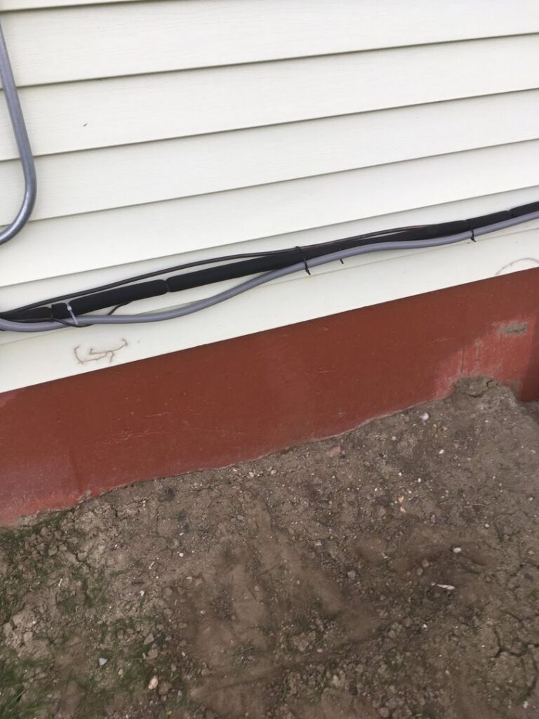 Refrigerant lines and electrical conduit running along an exterior wall, installed by Arrowhead Heating & Air Conditioning in Casper, WY.