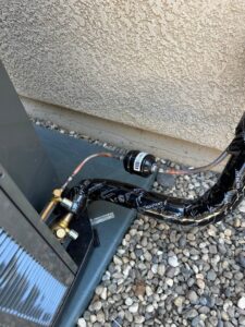 Close-up of insulated refrigerant lines and a filter drier connected to an outdoor HVAC unit by Ecology Air Innovations in Sacramento, CA.