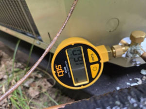A digital vacuum gauge checking refrigerant pressure on an HVAC unit by Orchard Heating-Cooling and Sheet Metal in Stow, OH.