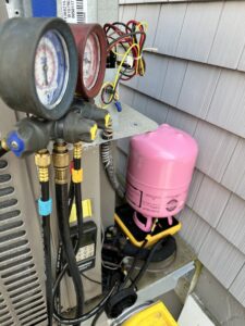 HVAC gauges connected to an outdoor unit for refrigerant recharge by Mueller Mechanical HVAC in Philadelphia, PA.