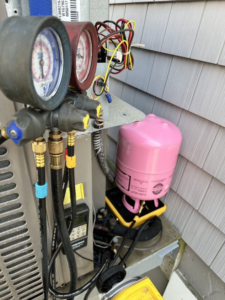 HVAC gauges connected to an outdoor unit for refrigerant recharge by Mueller Mechanical HVAC in Philadelphia, PA.