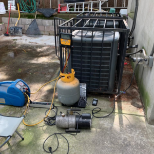 An outdoor HVAC unit with refrigerant recovery equipment set up for service by aghapy 1 in Jersey City, NJ