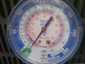 A refrigerant tank and gauges connected to an outdoor AC unit during service by J AND J HVAC L.L.C in Mesa, AZ