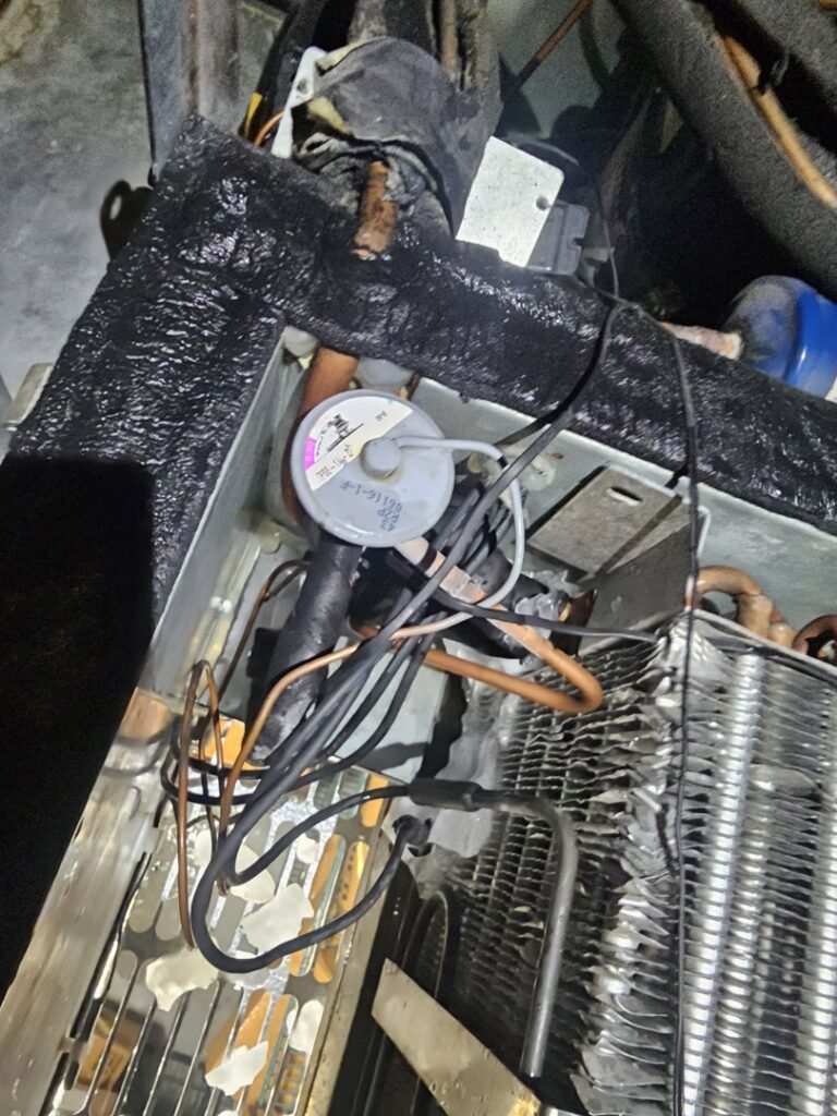 Close-up of internal components, including pipes and a pressure switch, within an HVAC or refrigeration unit by Henry Refrigeration & Hvac Utah in Ogden, UT.