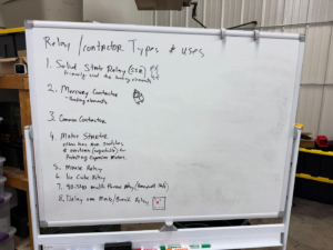 A whiteboard listing various relay and contactor types and their uses, relevant to HVAC systems, at Commercial Kitchen Services, LLC of Watertown, SD.