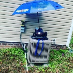 An outdoor air conditioning unit undergoing repair with tools and an umbrella for shade by Climate Mechanical in Dinwiddie, VA.