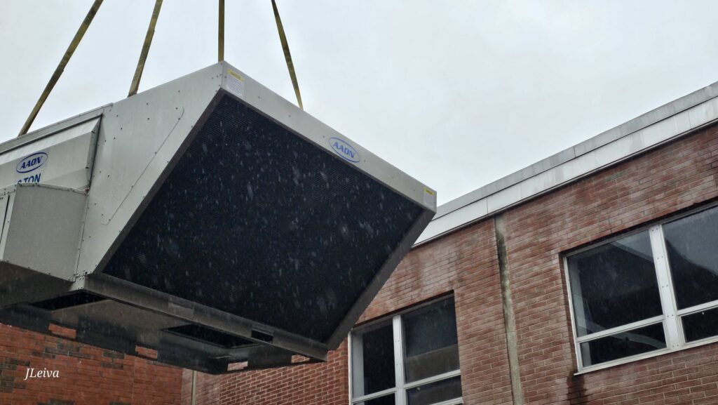 A large HVAC rooftop unit being lifted by a crane for installation by Clean Air Quality Service Inc in Hawthorne, NY