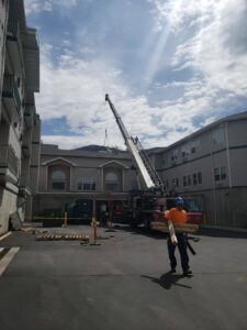A large HVAC rooftop unit being lifted by a crane for installation by Butte Tin Shop, Inc. in Butte, MT.