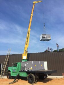 HVAC technicians overseeing a rooftop unit installation with a crane for Comfort Engineering Co Inc in Tupelo, MS