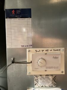 A service record sticker from Your HVAC Guy next to an Aprilaire humidifier control on ductwork in Aurora, IL.