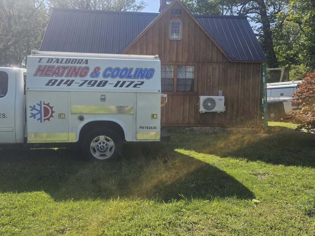 A T. D'Albora Heating and Cooling service truck parked next to a house with a newly installed mini-split unit in Erie, PA.