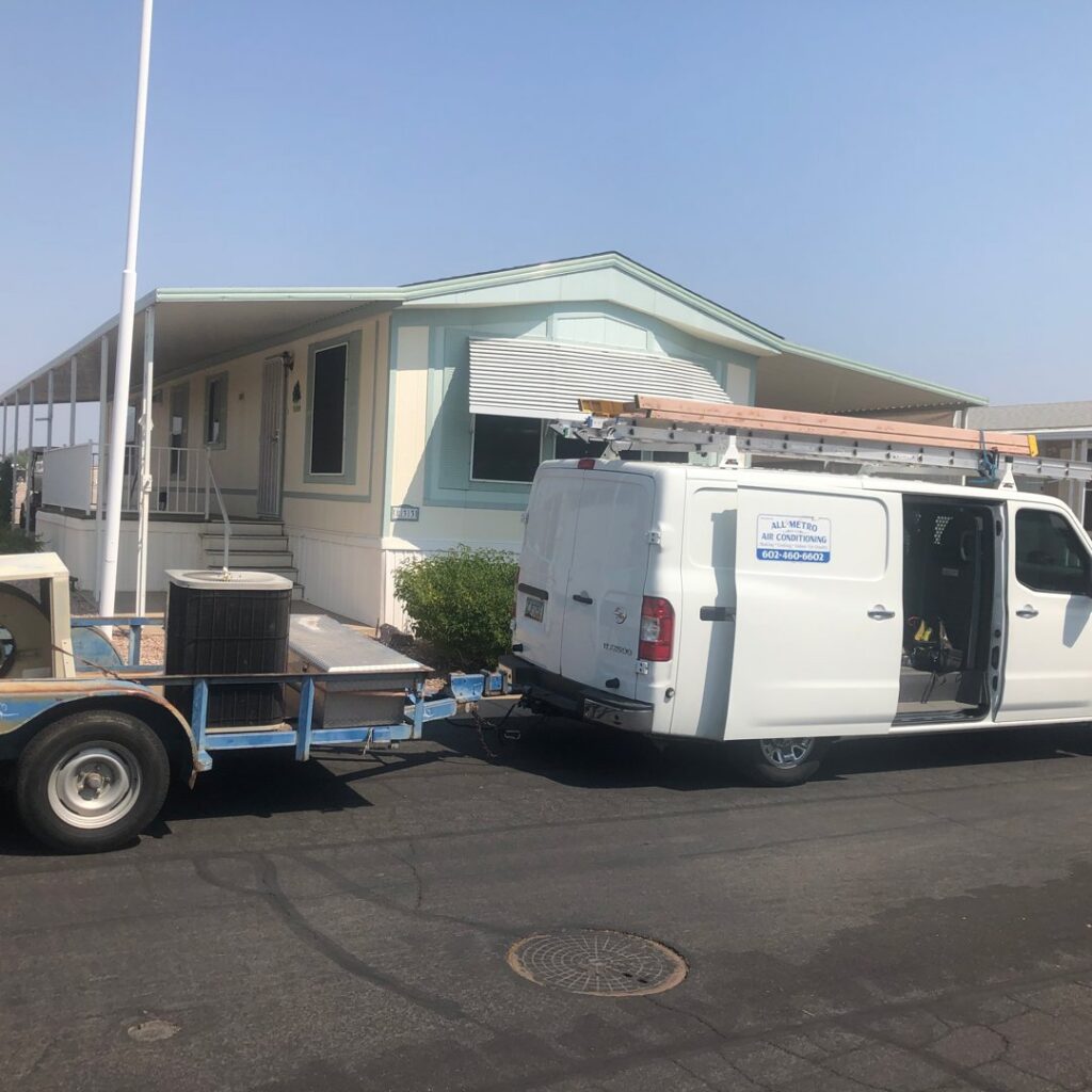 An All Metro Air Conditioning service van and trailer with an outdoor AC unit at a job site in Apache Junction, AZ.