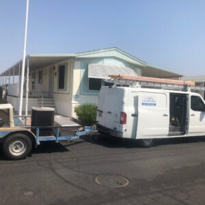 An All Metro Air Conditioning service van and trailer with an outdoor AC unit at a job site in Apache Junction, AZ.