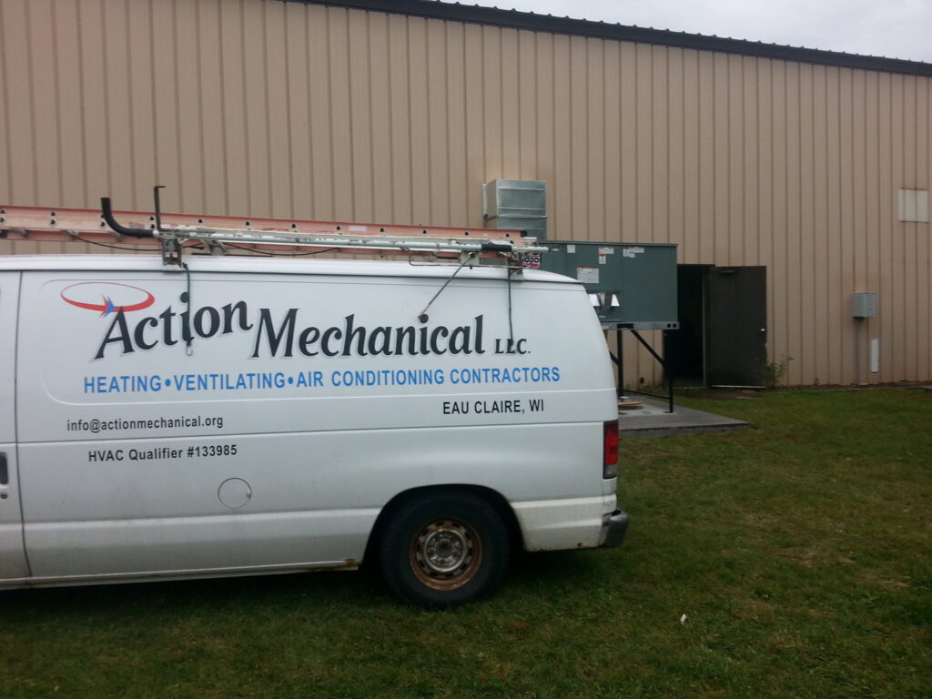 An Action Mechanical LLC service van parked outside a commercial building with an HVAC unit, in Eau Claire, WI.