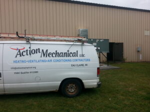 An Action Mechanical LLC service van parked outside a commercial building with an HVAC unit, in Eau Claire, WI.