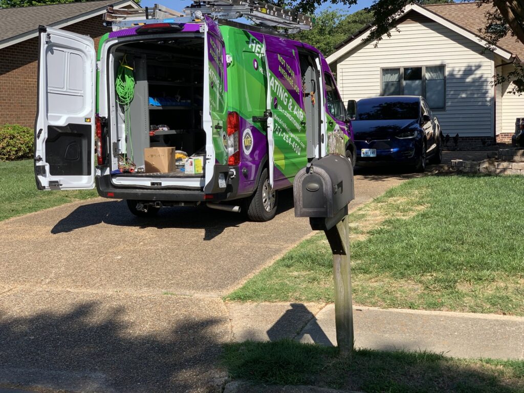 A Hendrix Heating & Air service van with open doors, showing tools and equipment at a job site in Newport News, VA.