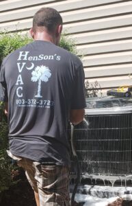 A Henson's HVAC LLC service van with ladders towing a trailer delivering new HVAC equipment in Rock Hill, SC.