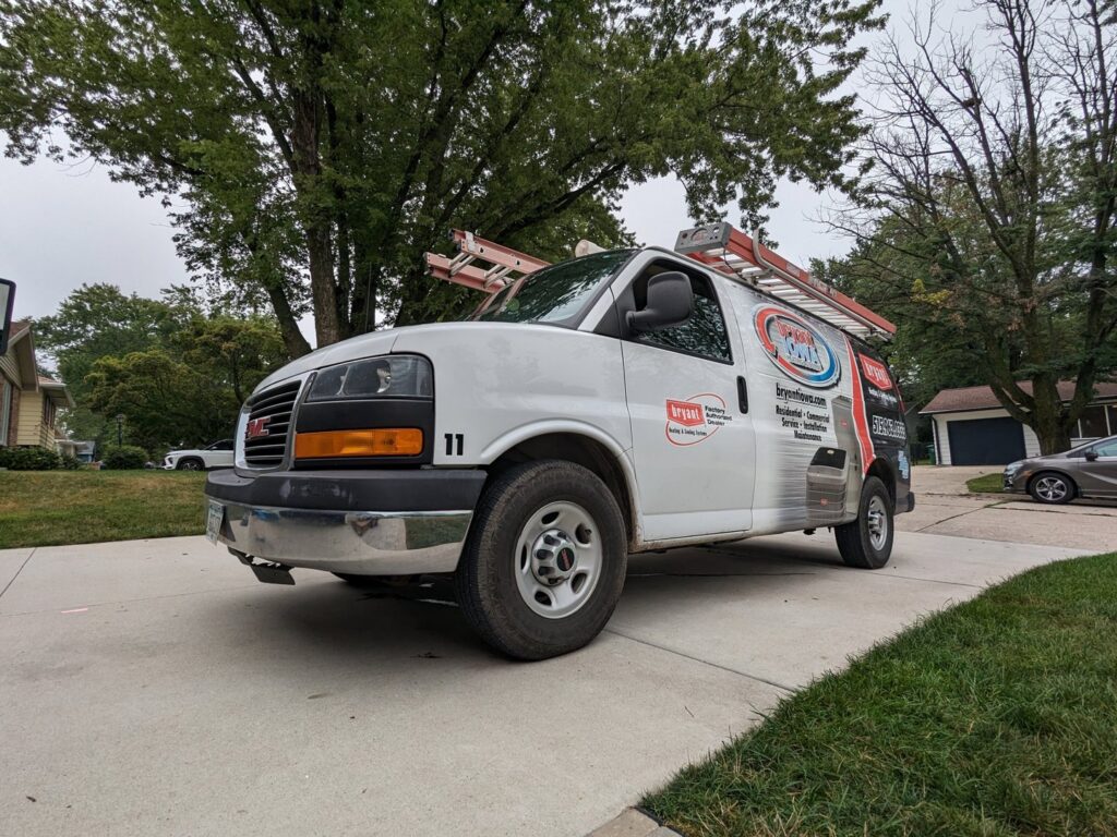 A branded HVAC service van with a ladder on top for Marie Keding Bryant Iowa Heating and Cooling in Ankeny, IA.