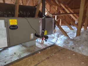 A new HVAC system installation in an attic, showing insulation and piping by Comfort Hounds Heating & Cooling in Raleigh, NC.