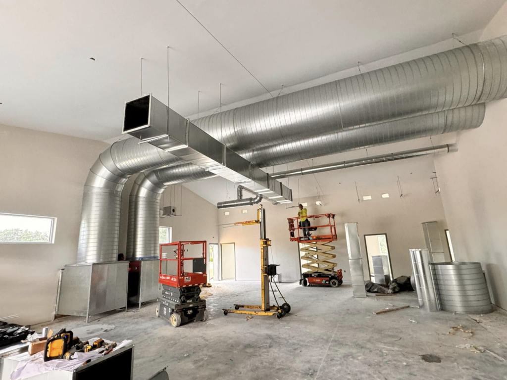 HVAC system installation in progress with technicians on lifts by Buck'n Bull HVAC Solutions in Wilmington, NC