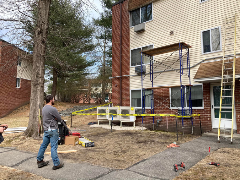 An HVAC system installation job site with outdoor condenser units and scaffolding for Express Plumbing in Hatfield, MA.