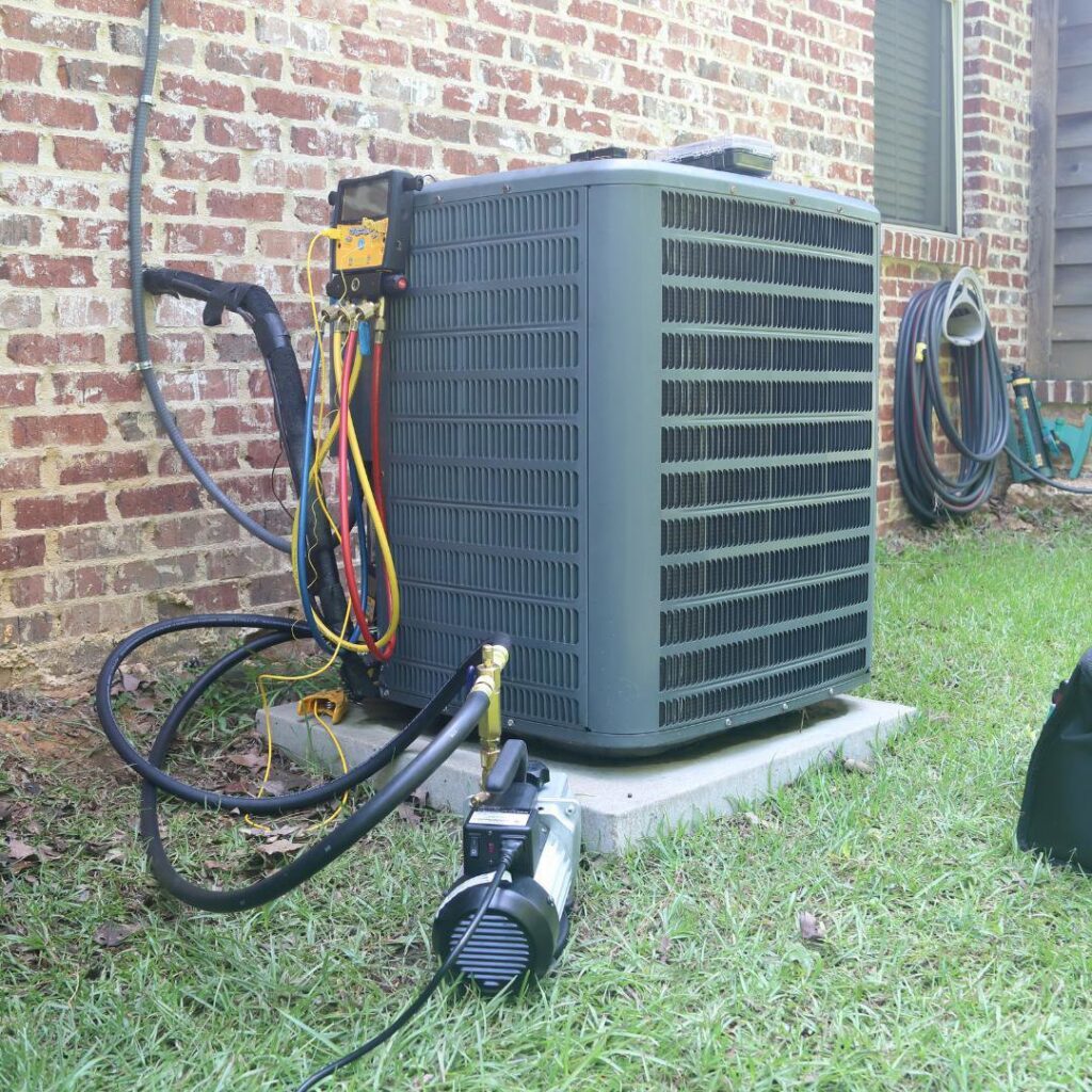 An HVAC technician performing system installation or service on an outdoor AC unit for Reliance Home Comfort in Hampton, VA.