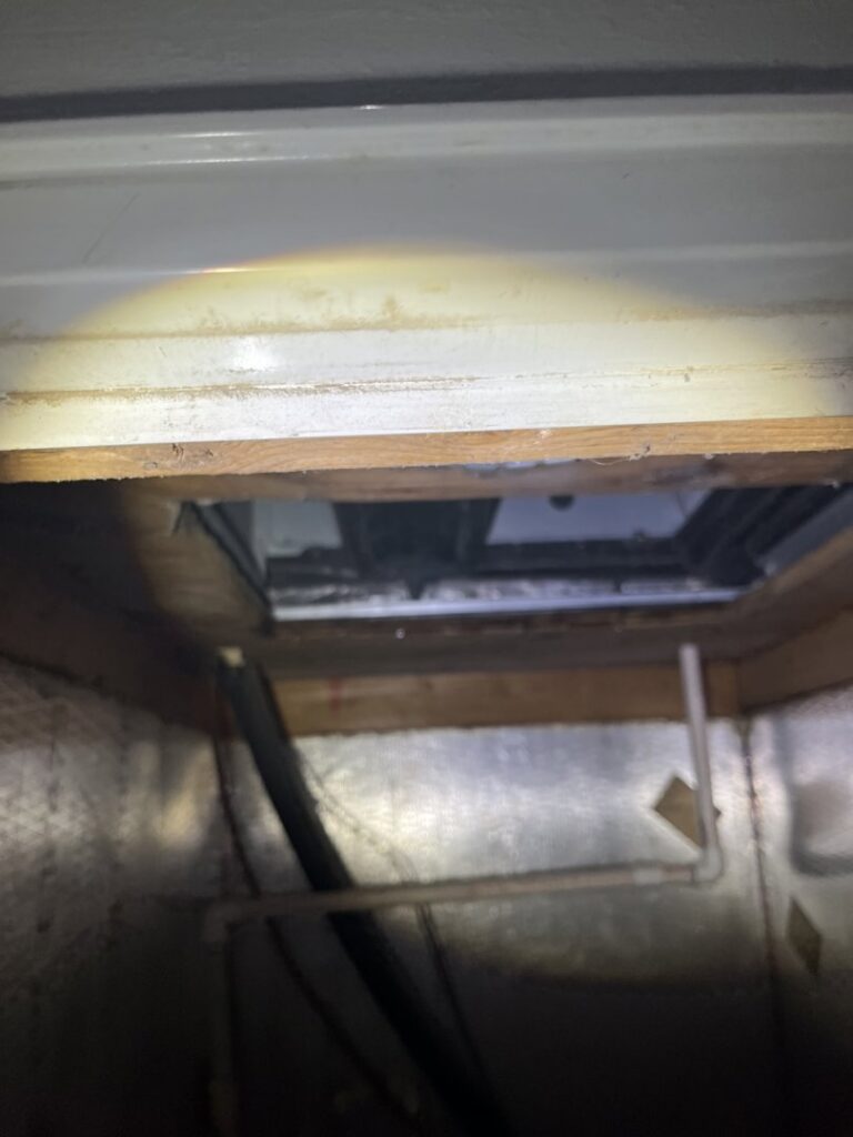 Interior view of an HVAC system, possibly an air handler or ductwork, during an inspection by Cooler Solutions LLC Heating & Air in Gulfport, MS.