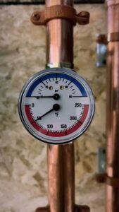 A close-up of a pressure and temperature gauge on copper piping, part of an HVAC system by HVAC Fellows in Boston, MA.