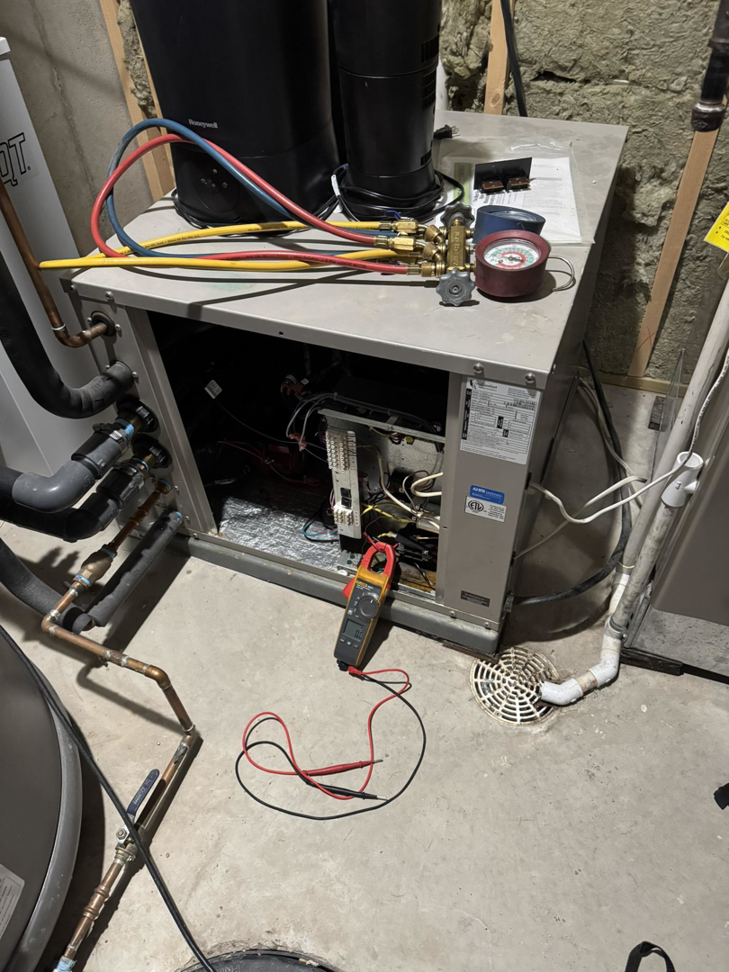 A technician performing diagnostic and repair work on an indoor HVAC system at Golden Heating and Air LLC in Arvada, CO.