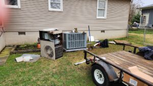 Old HVAC units being removed during a system replacement, with a new condenser unit installed in the background by Bama Air Systems in Cullman, AL.