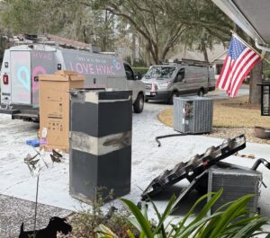 Love HVAC LLC vans parked at a residence during an HVAC system replacement, with old units and new equipment visible in Bluffton, SC.