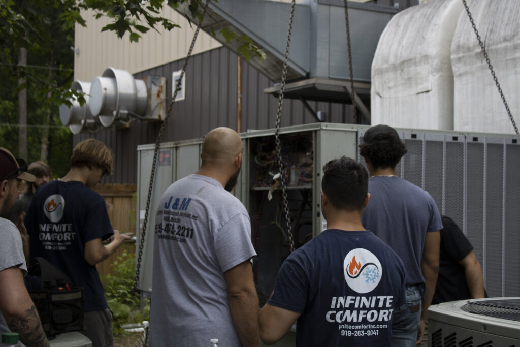 A team of Infinite Comfort technicians servicing a commercial HVAC unit in Youngsville, NC.